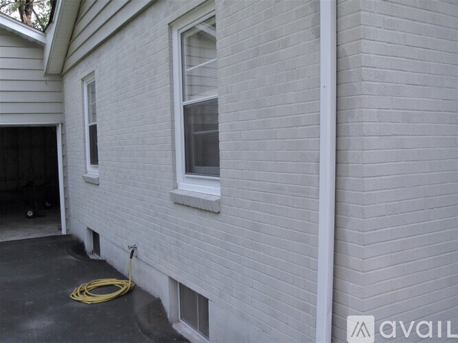 A yellow hose is on the ground next to a white wall.