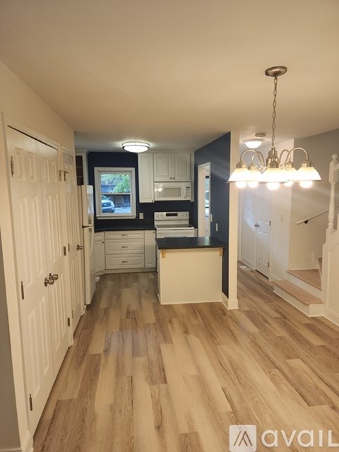 A kitchen with wooden floors and white cabinets.