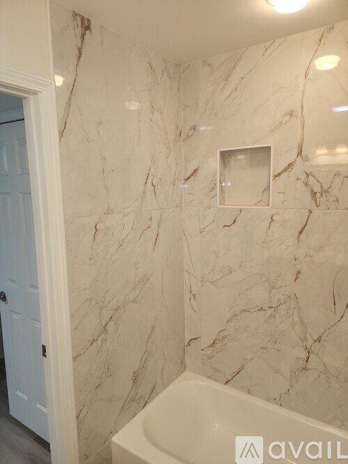 A bathroom with marble tiles and a white tub.