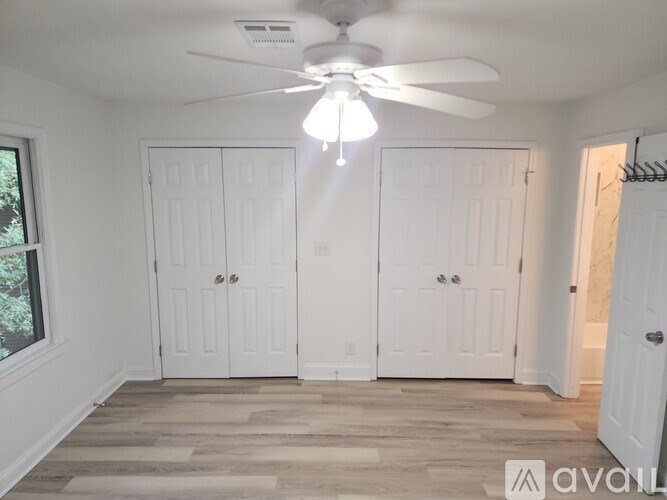 A room with a ceiling fan and three white doors.