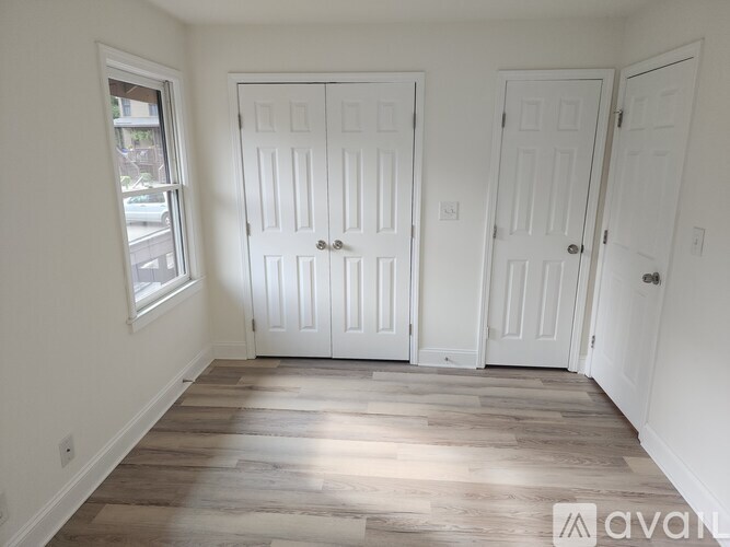 A room with two white doors and a window.