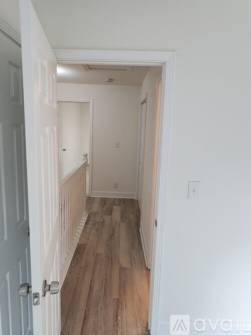 A hallway with a wooden floor and white walls.