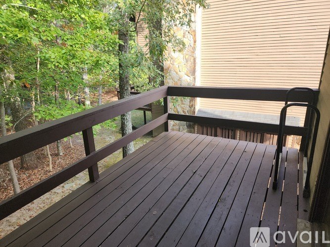 A wooden deck with a railing and trees in the background.