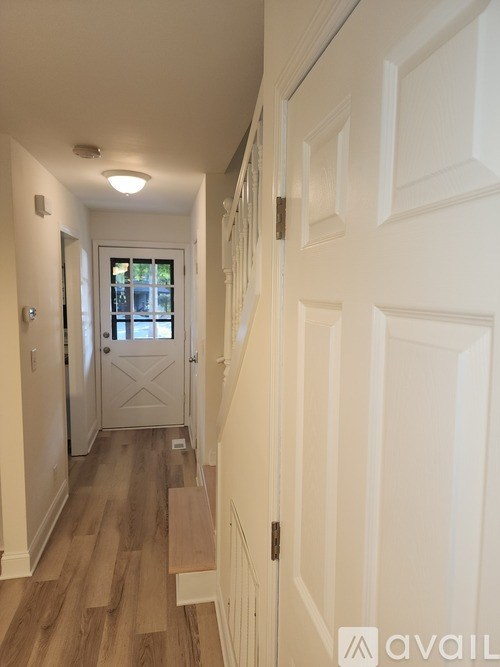 A hallway with a white door and a window.