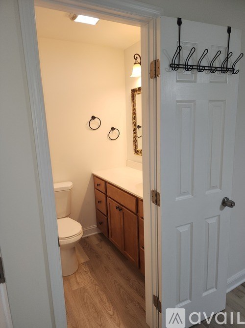 A white door is open to a small bathroom with a toilet and a vanity.