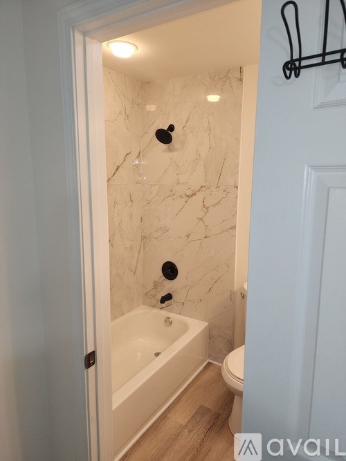 A bathroom with a marble wall and a white door.