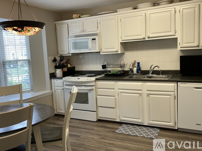A kitchen with white cabinets and a black countertop.