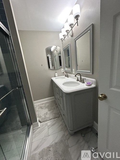 A bathroom with a sink, mirror, and a glass shower door.