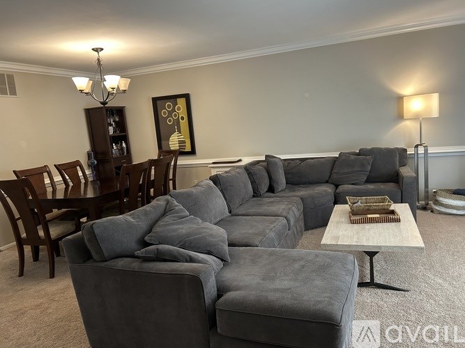 A living room with a grey sofa set and a wooden dining table.