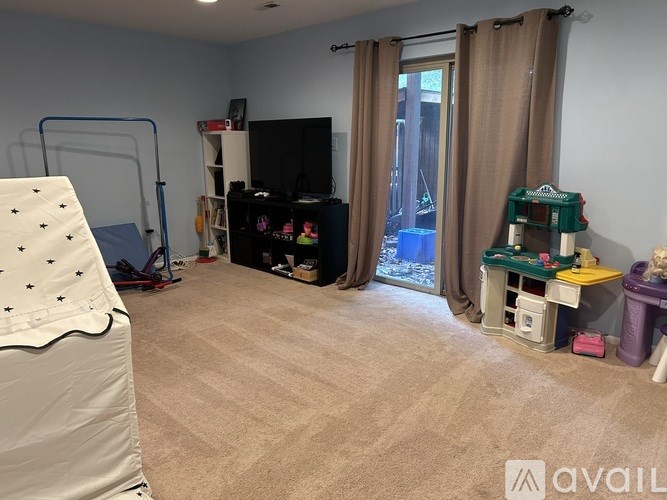 A room with a bed, a TV, and a play area with toys.