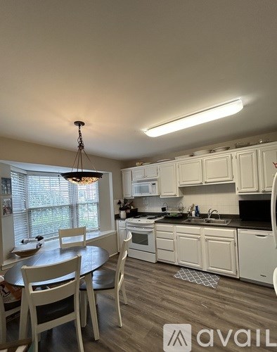 A kitchen with white cabinets and a round table with chairs.