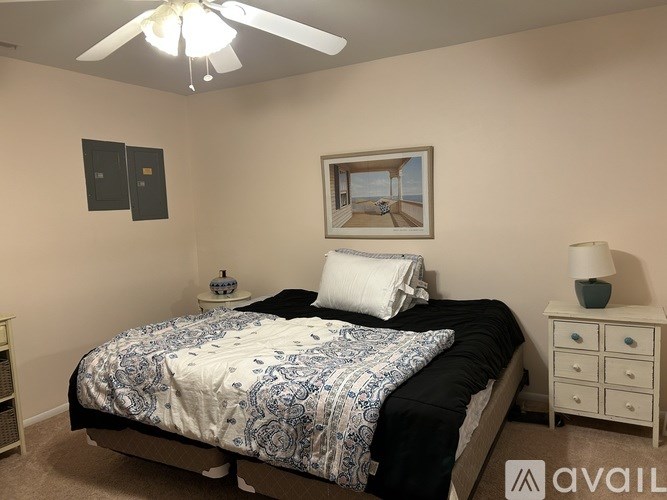 A bedroom with a bed, nightstand, and a ceiling fan.
