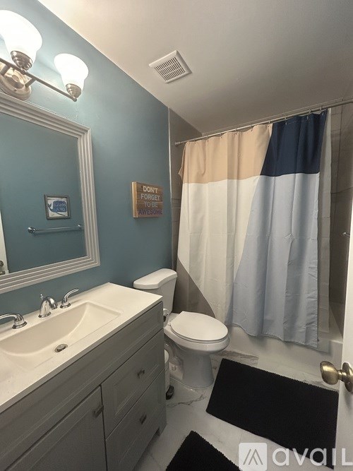 A bathroom with a toilet, sink, and shower curtain.