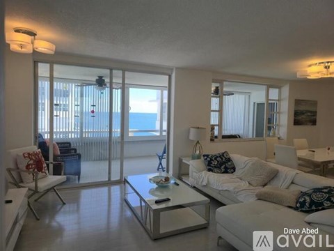 A living room with a white couch and a glass table with a vase on it.