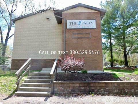 A small building with a sign that reads "The Falls at Trails End" and a phone number below it.