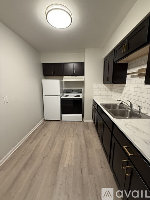 A kitchen with black cabinets and a white fridge.