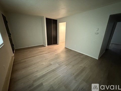 A room with wooden flooring and a door on the right side.