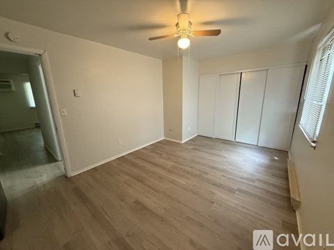 A room with a ceiling fan and wooden flooring.