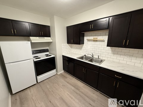 A kitchen with white appliances and black cabinets.