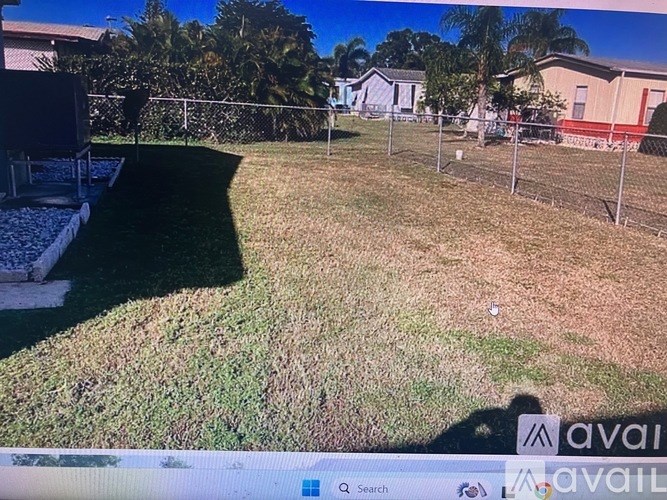 A grassy area with a fence and a house in the background.