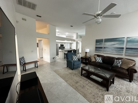 A living room with a brown couch and a fan.