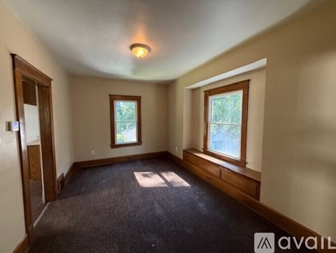 A room with a carpeted floor, two windows, and a door.