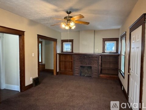 A living room with a fireplace and a ceiling fan.