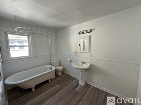 A white bathroom with a claw foot tub and wooden floors.