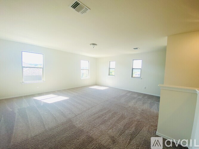 A spacious room with carpeted floor and three windows.