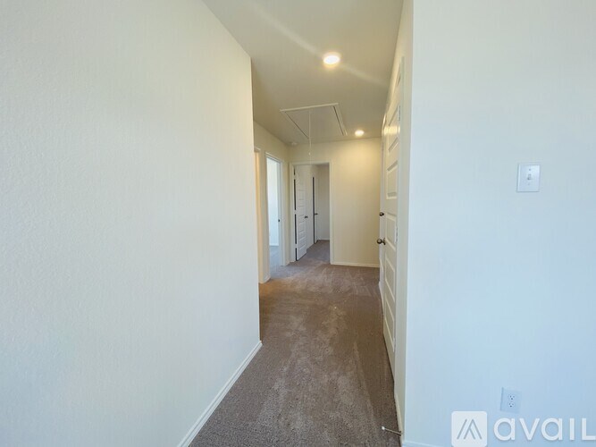 A long hallway with carpeted floors and white walls.