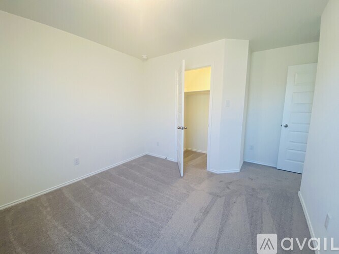 A room with carpeted floor and white walls, with a doorway leading to another room.