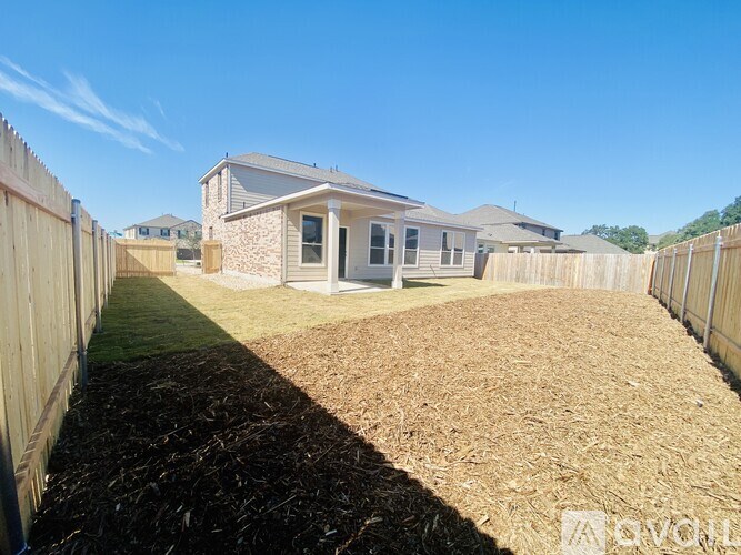 A house with a brown lawn and a wooden fence.