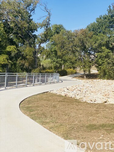 A pathway with a metal railing on the left side and a grassy area on the right.