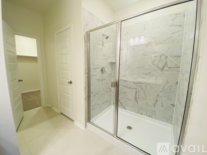 A bathroom with a glass shower door and a white door.