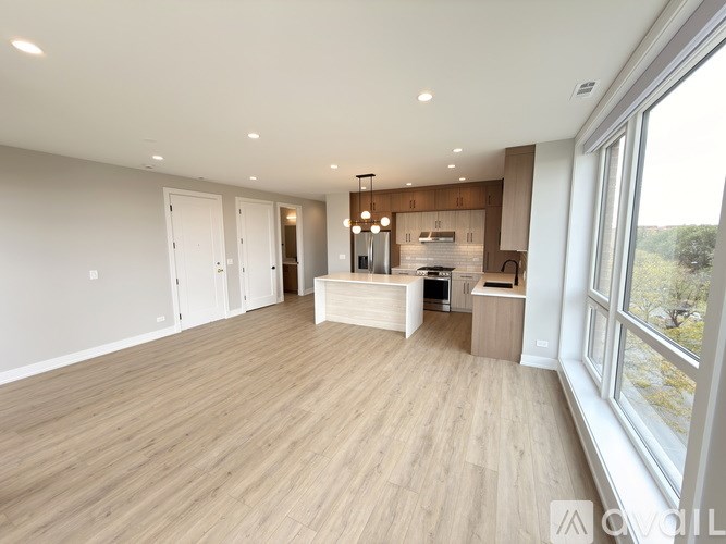 A spacious kitchen with wooden flooring and a large window.