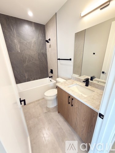 A bathroom with a toilet, sink, and a mirror.