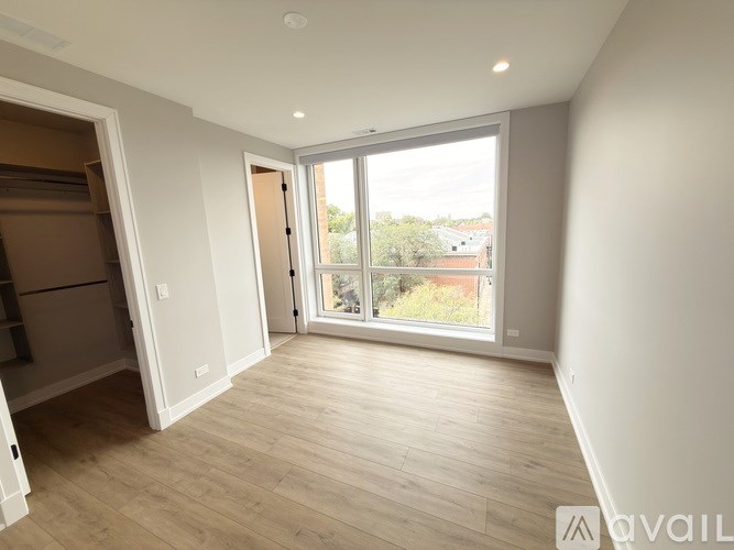A spacious room with wooden flooring and a large window.