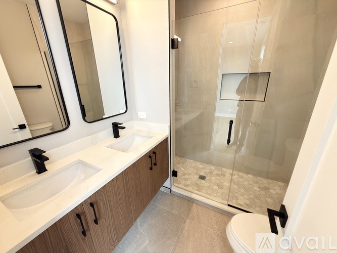 A modern bathroom with a glass shower stall and double sinks.