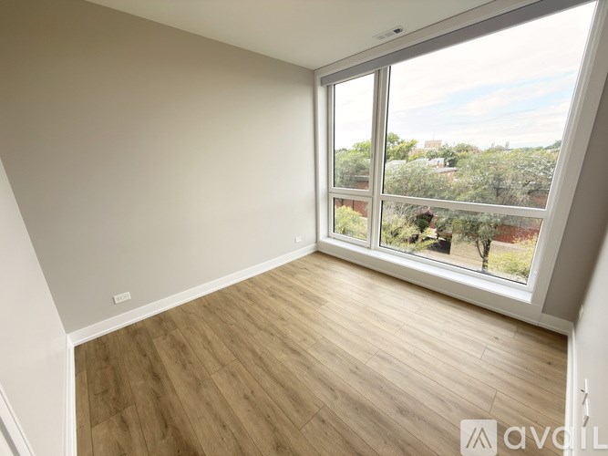 A room with wooden flooring and a large window overlooking a garden.
