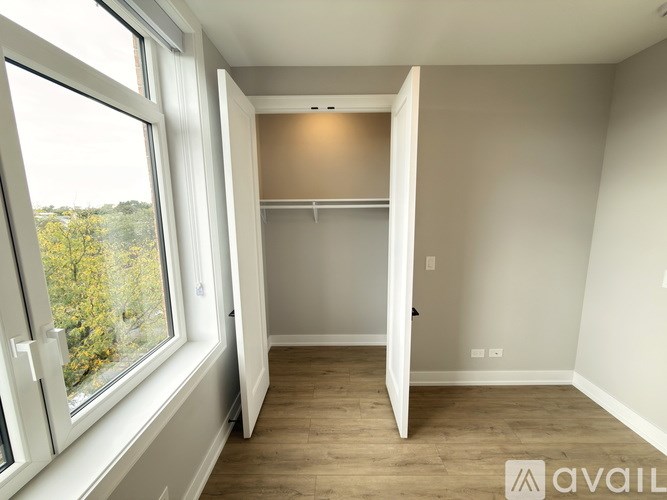 A room with a large window and a door leading to another room.
