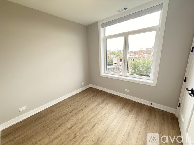 A room with a large window and wooden flooring.