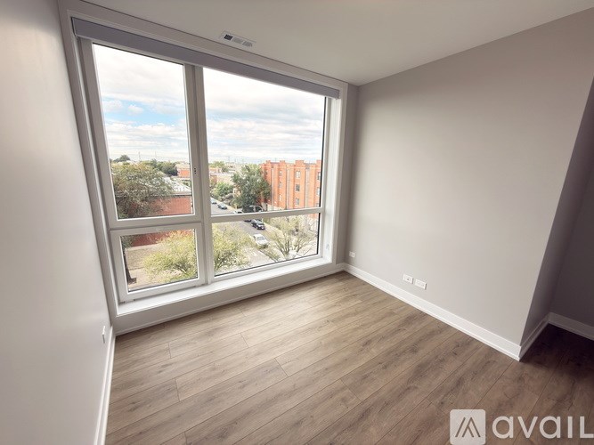 A room with a large window overlooking a parking lot and buildings.
