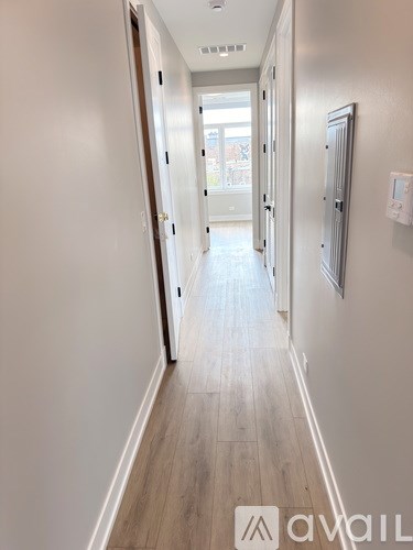 A long hallway with wood floors and white walls.