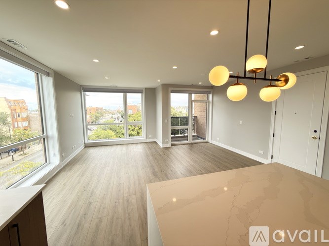 A spacious room with wooden floors and a large window overlooking a garden.