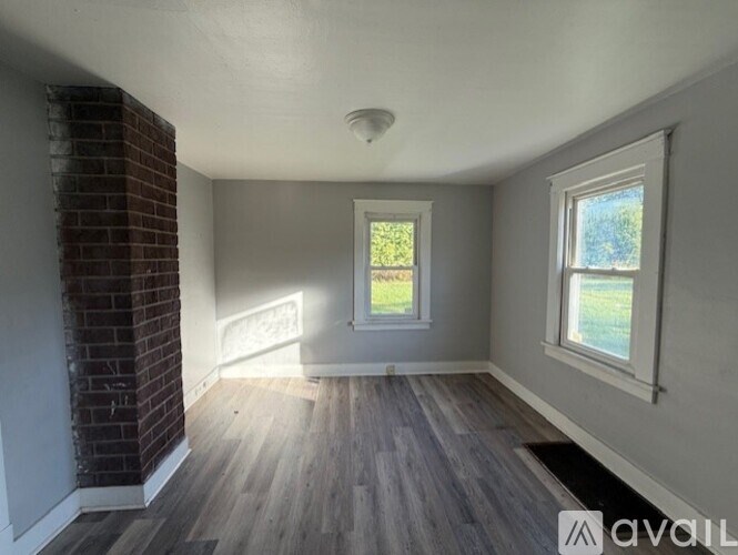 A room with a brick wall and wooden flooring is available for rent.