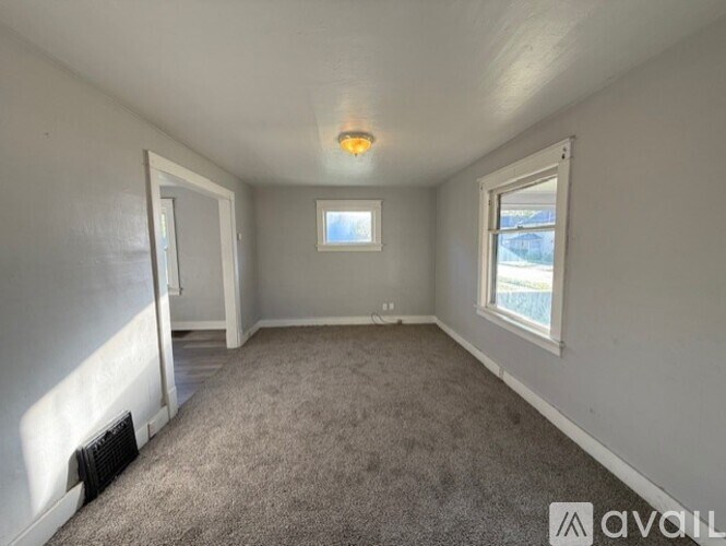 A room with a carpeted floor, a window, and a door.
