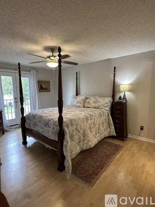 A bedroom with a four-poster bed and a ceiling fan.