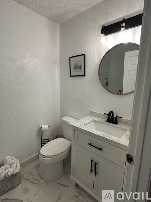 A bathroom with a toilet, sink, and mirror.