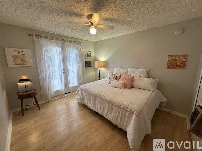 A bedroom with a bed, a lamp, and a ceiling fan.
