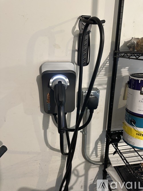 A black and silver electric car charging station with a cable plugged in.